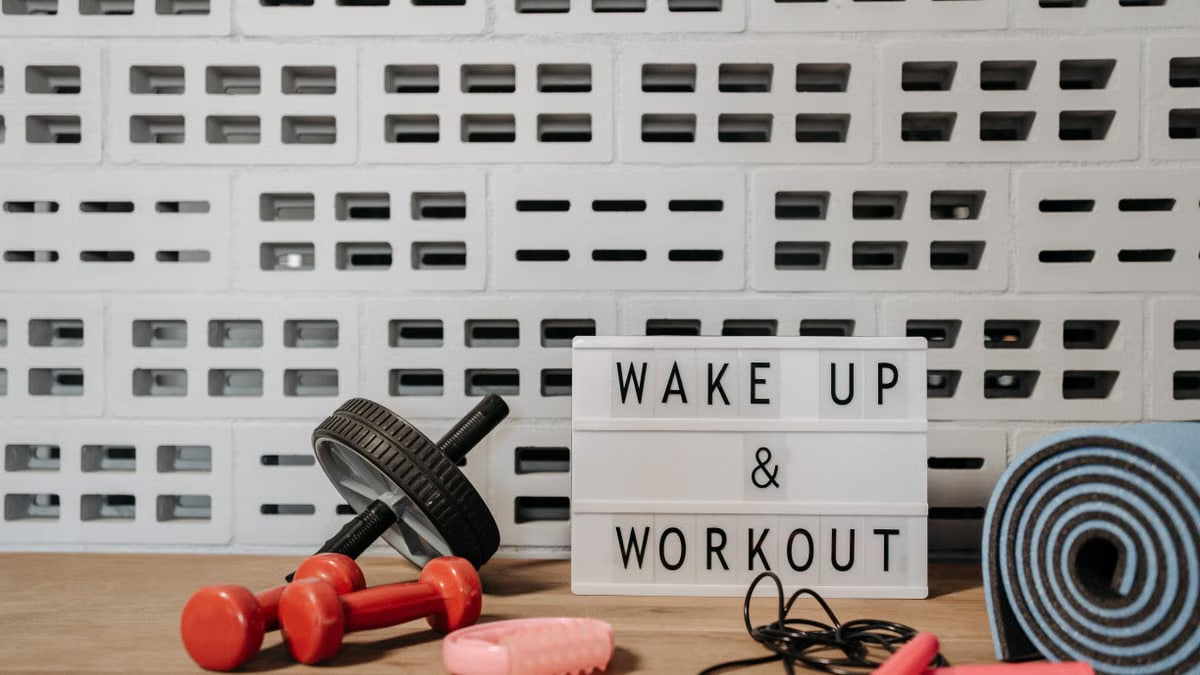 Fitness gear and motivational sign in home gym setup against a brick wall.
